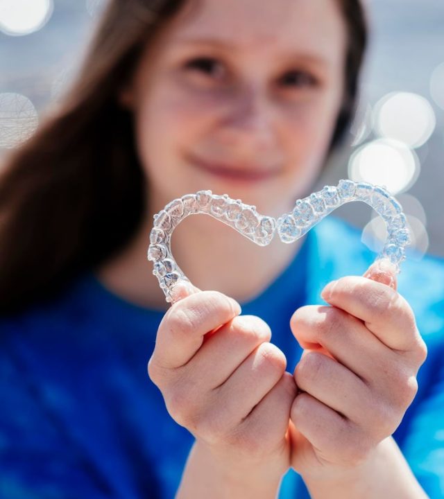 dental-care-smiling-beautiful-girl-holding-heartshaped-aligners-plastic-retainers-teeth-alignment_114354-6401